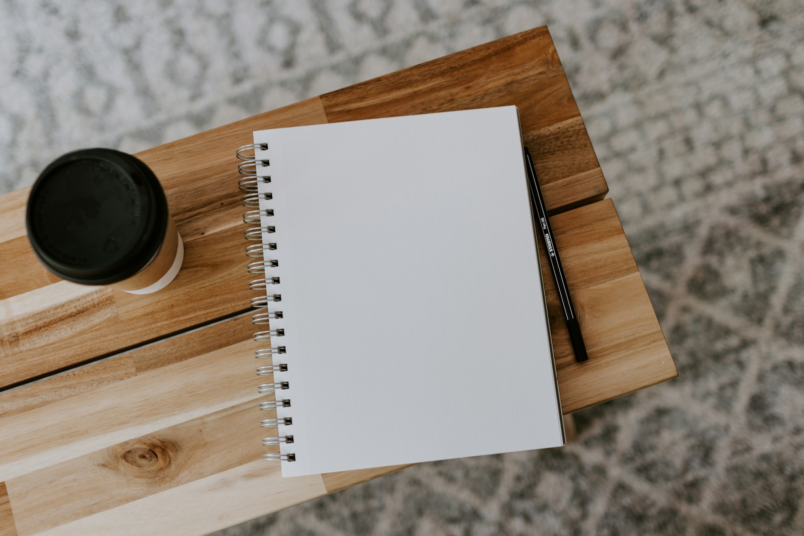 Notebook and pen on a wooden table, ready for a shopping list