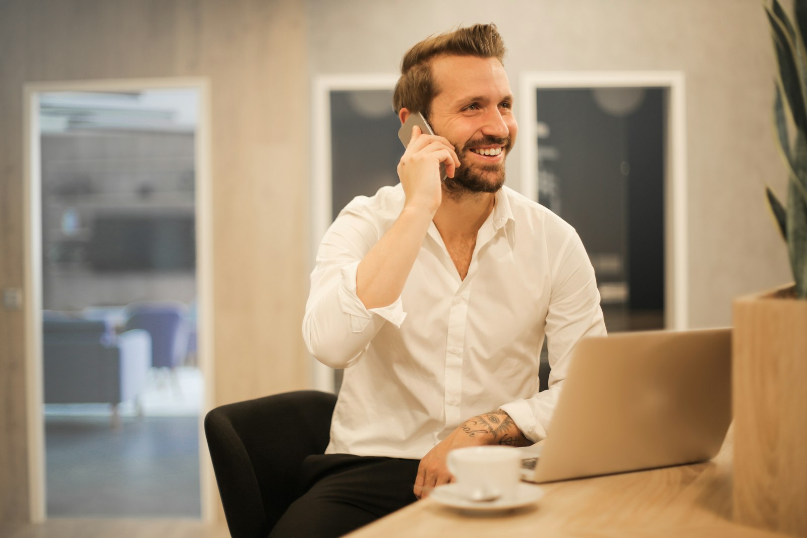Smiling man on a phone call with a laptop open in front of him